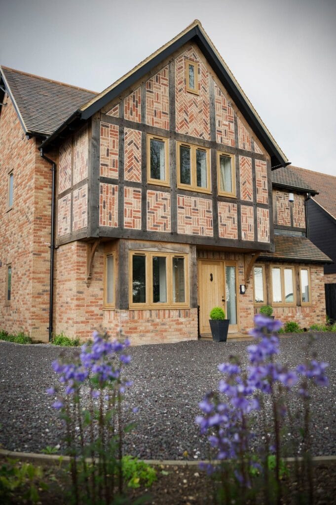 Oak-framed entrance porch on a traditional brick and timber-framed home with glazed side panels and a solid wood door