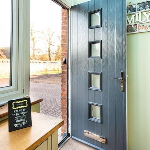 Slate grey composite front door with four square glazed panels, viewed from inside a hallway