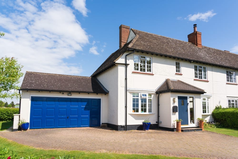 White render semi-detached house with white uPVC windows, blue front door and matching blue garage door
